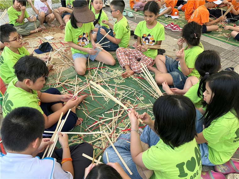 A group of children sitting on the ground with sticks
Description automatically generated
