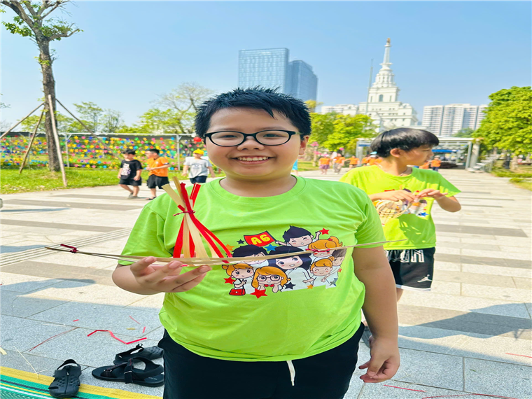A child in green shirt holding a slingshot
Description automatically generated