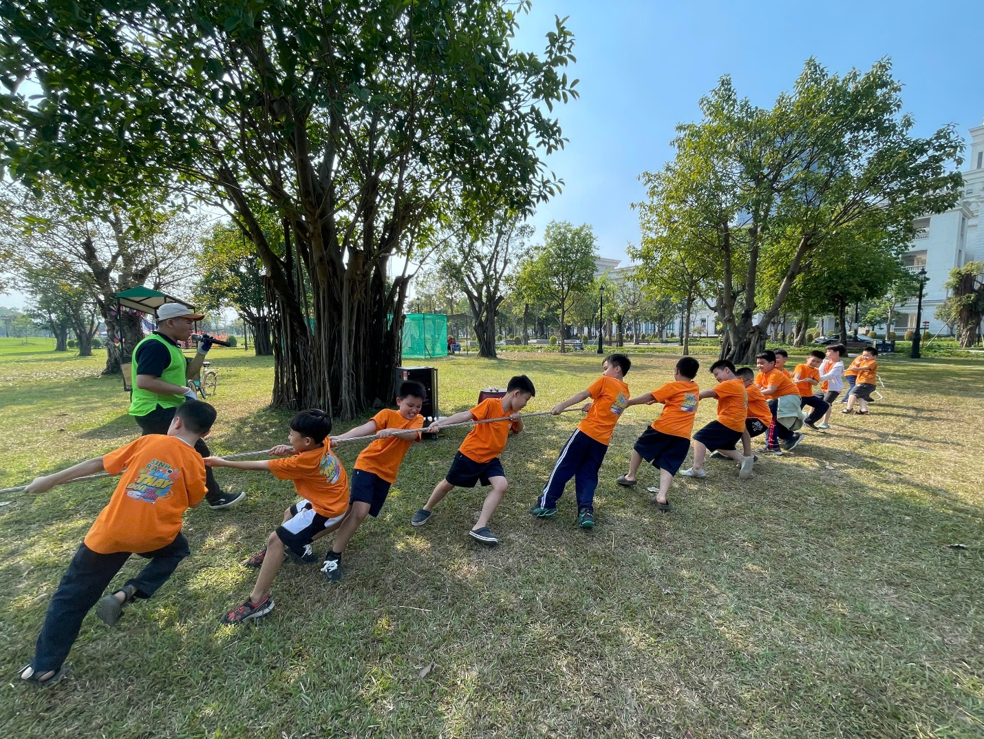 A group of kids in orange shirts pulling a rope

Description automatically generated