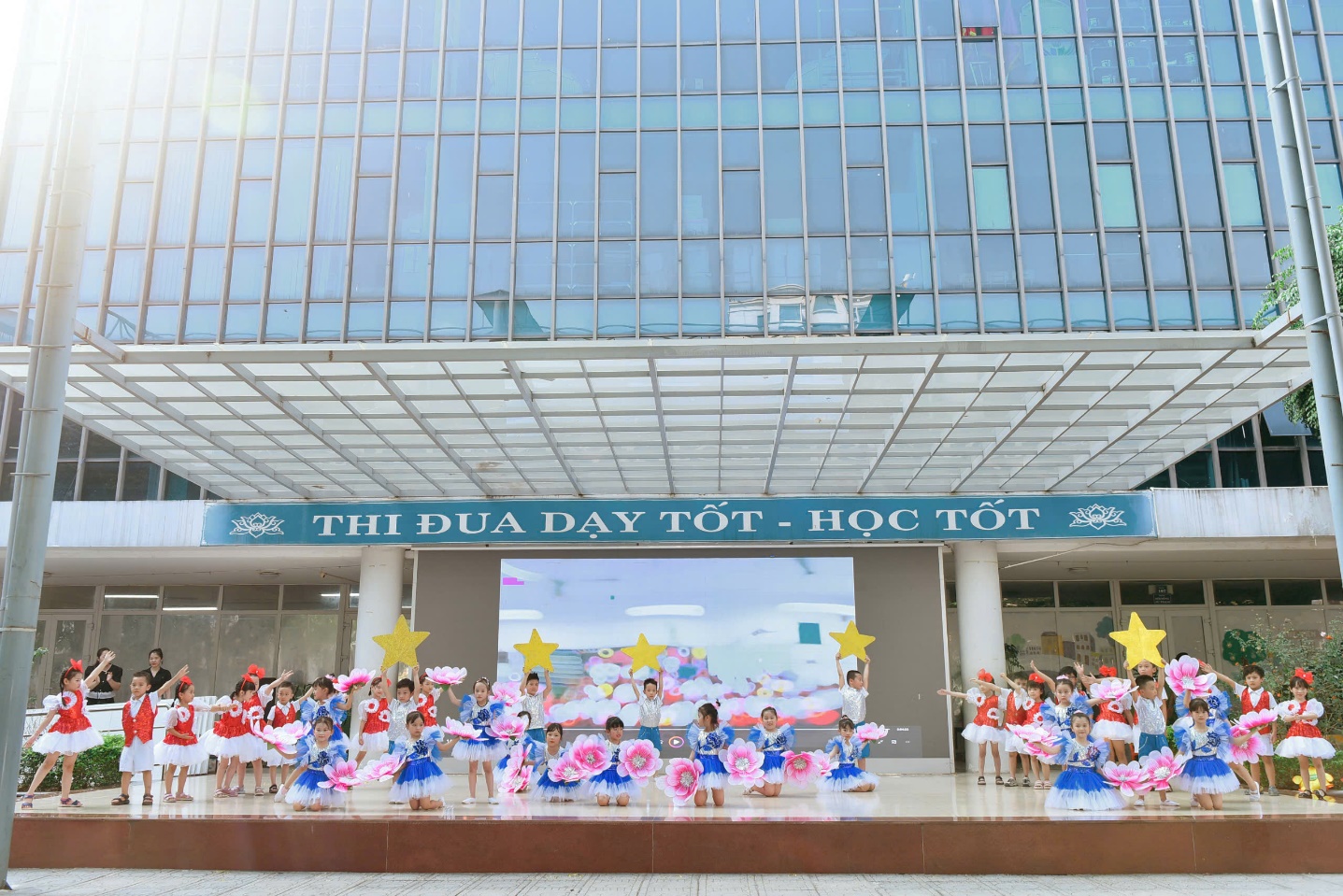 A group of children performing in front of a building

Description automatically generated
