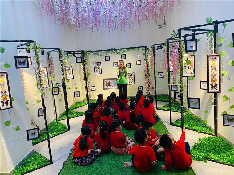 A group of children sitting on the floor in a room with a person standing in front of them

Description automatically generated