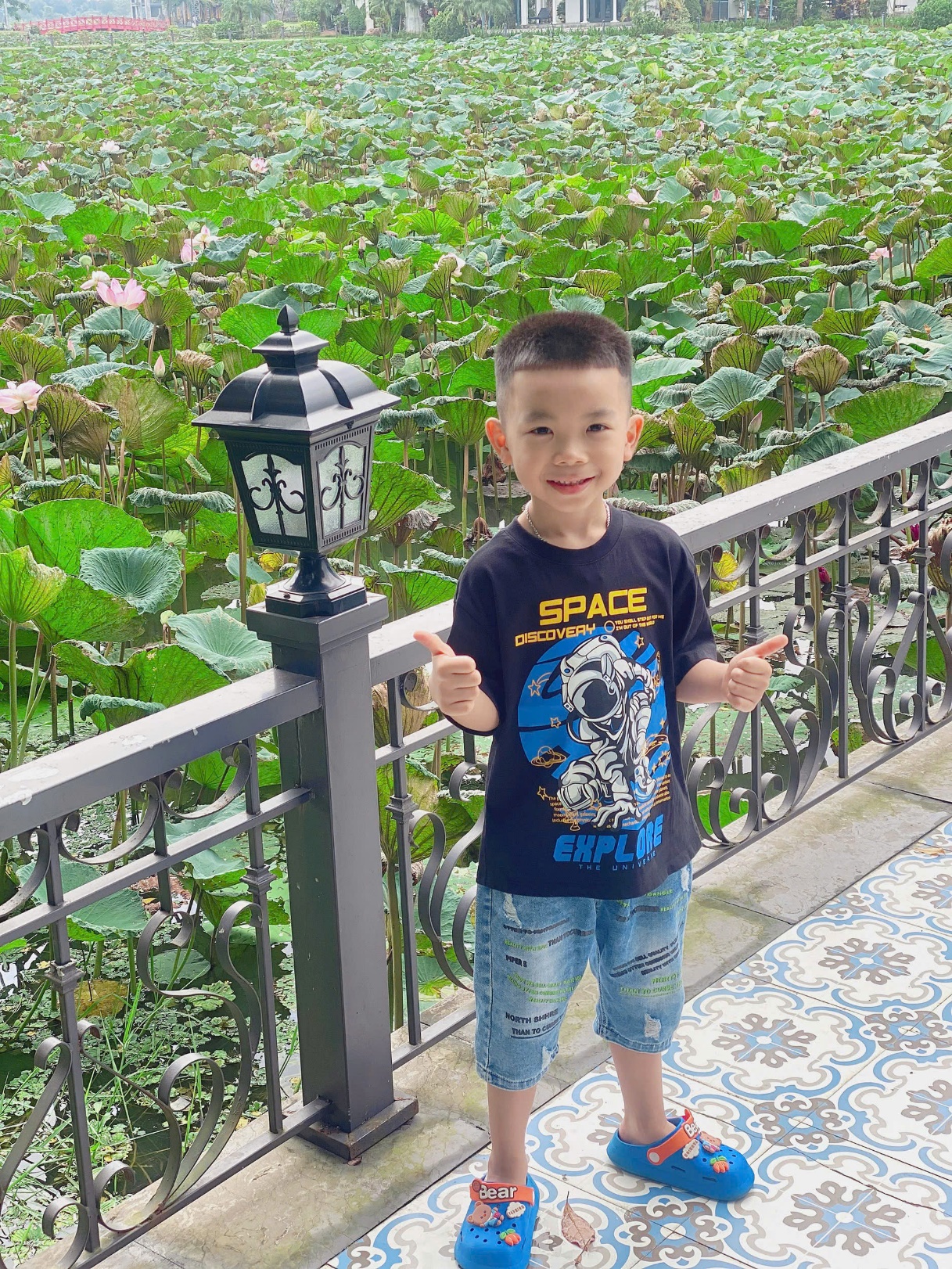 A child standing next to a fence and a lamp
Description automatically generated