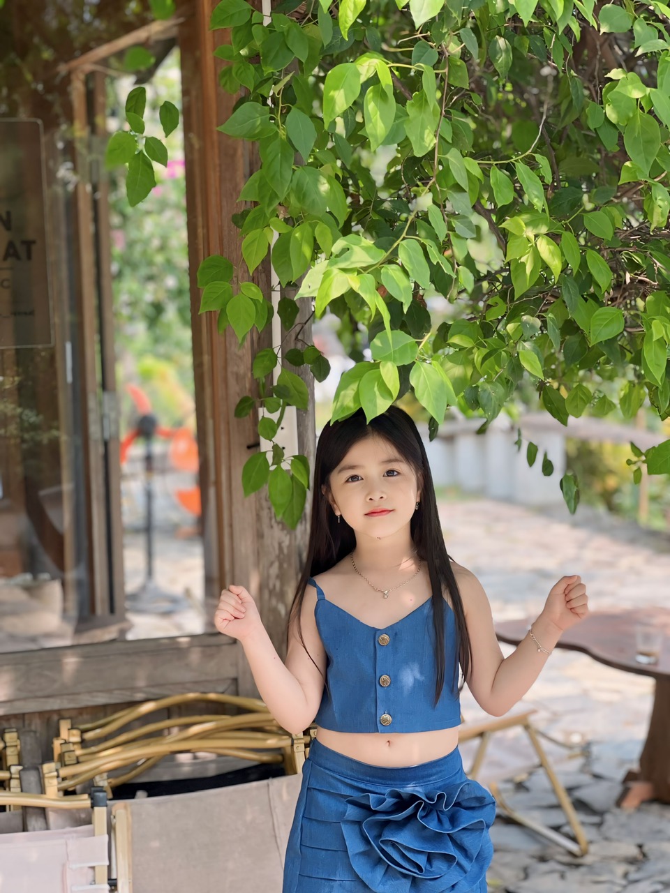 A child standing under a tree
Description automatically generated