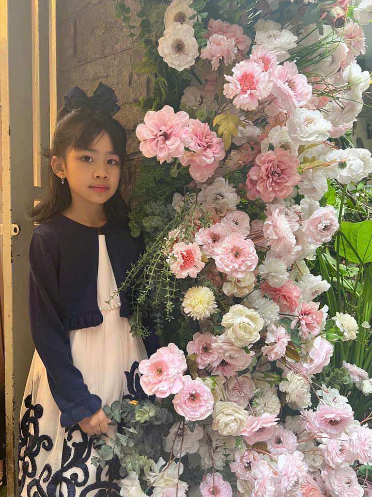 A child standing next to a large flower arrangement
Description automatically generated