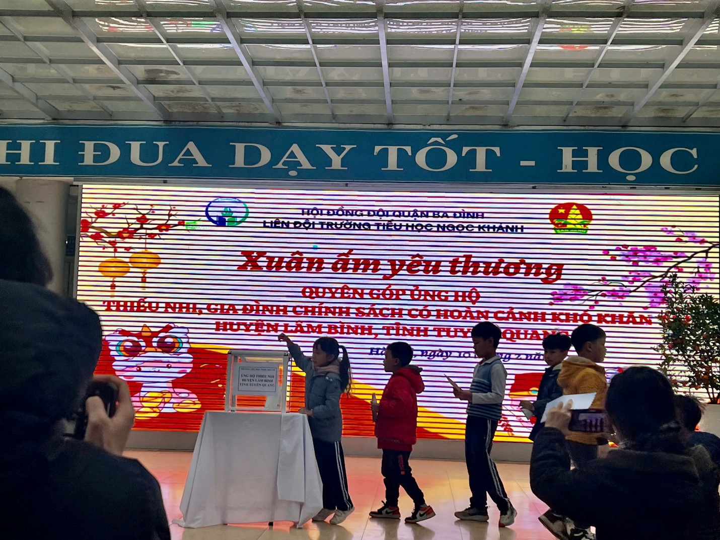 A group of children standing in front of a large sign

Description automatically generated