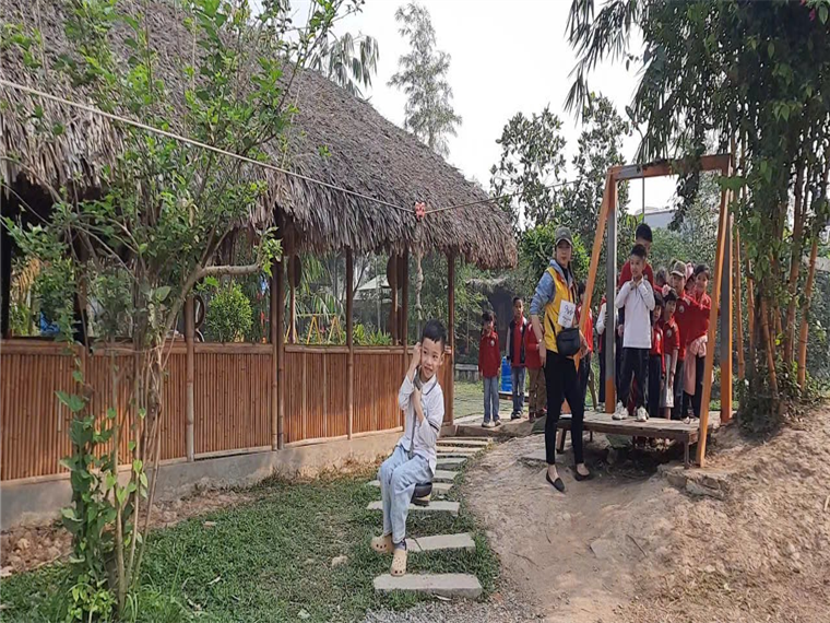 A person sitting on a step outside with a wooden pole

Description automatically generated