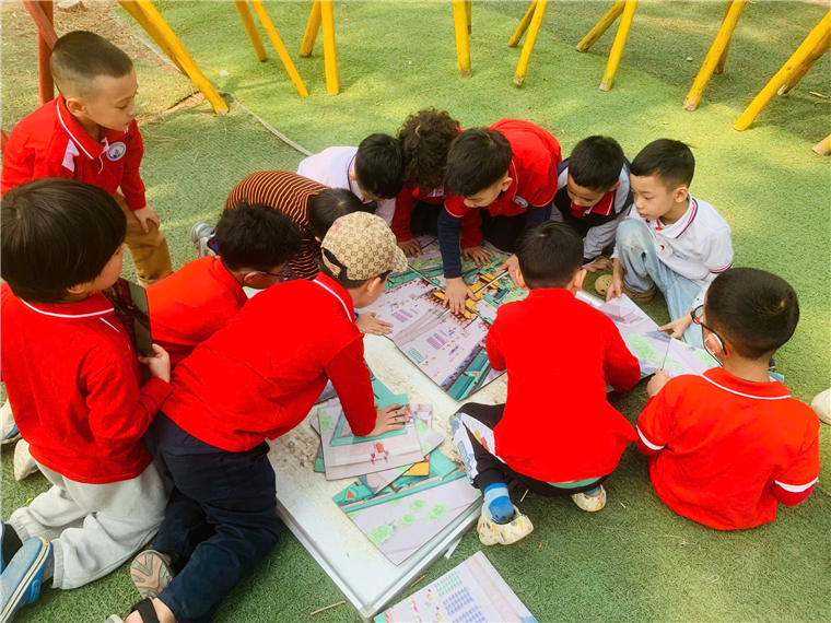 A group of children in red shirts sitting on the ground

Description automatically generated